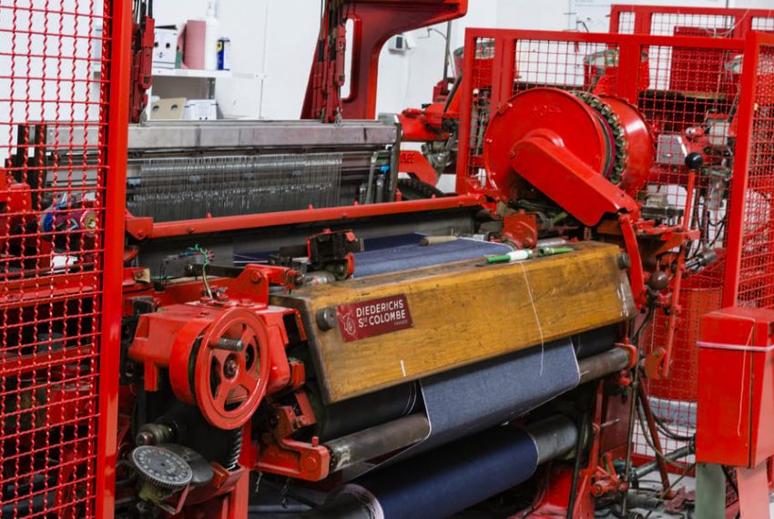 Aperçu d'une machine historique industrielle, un métier à tissr rouge et bois pour la confection du tissu.